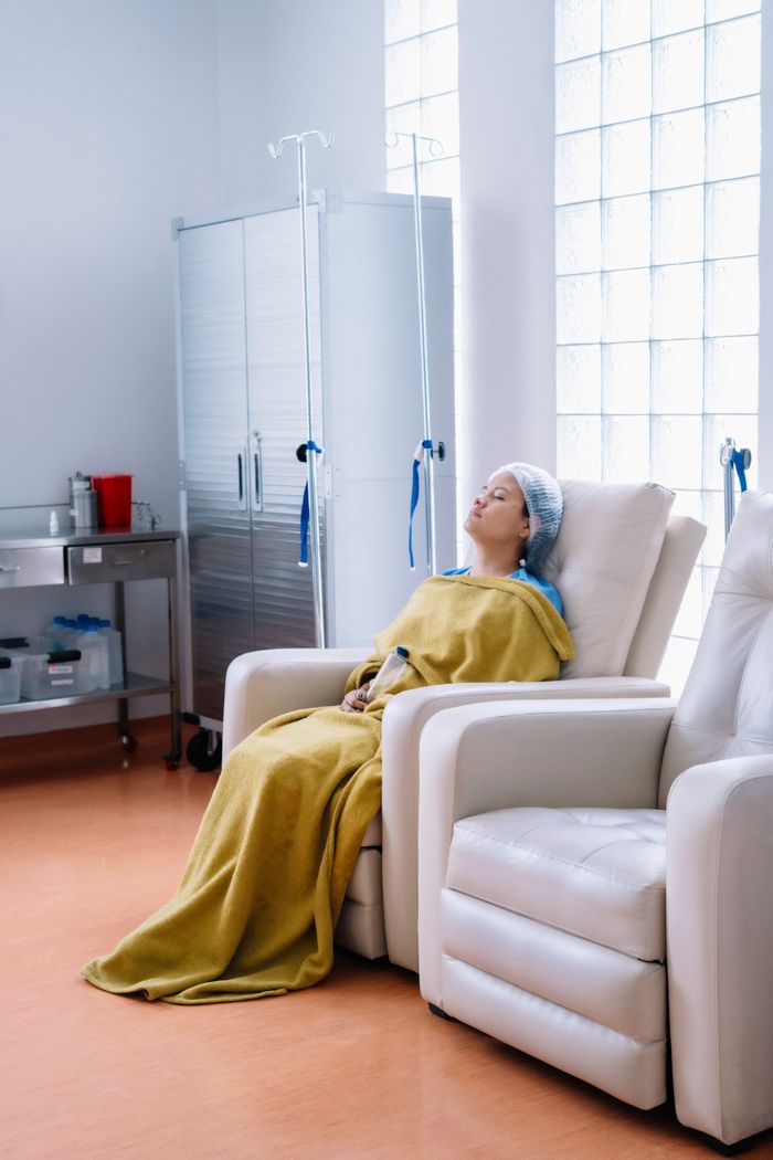 Woman resting in hospital recovery room, wrapped in a blanket, illustrating post-surgery care.